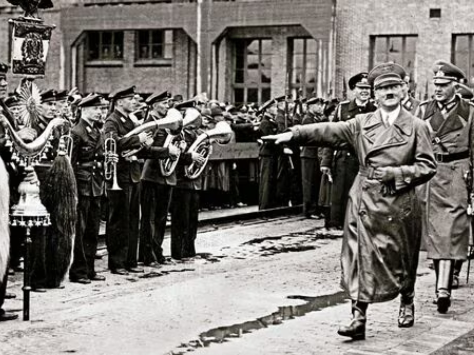 Adolf Hitler and Field Marshal von Blomberg greeted by a military band and onlookers during their arrival, circa 1935.