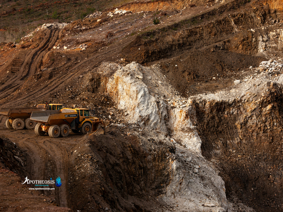 Open‑pit mining site with large trucks and terraced rock formations representing Critical Mineral extraction.