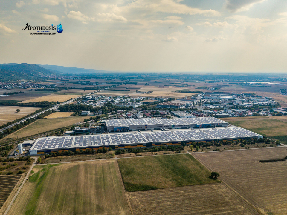 Aerial view of warehouses with solar panels surrounded by farmland, representing Green Supply Chains and modern low carbon logistics.